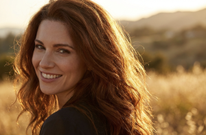 Alt: Woman smiling in a sunlit field