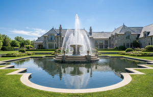 Alt: Large fountain in front of an elegant mansion