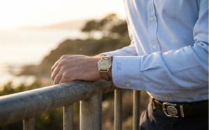 Alt: Man in blue shirt with wristwatch leaning on railing
