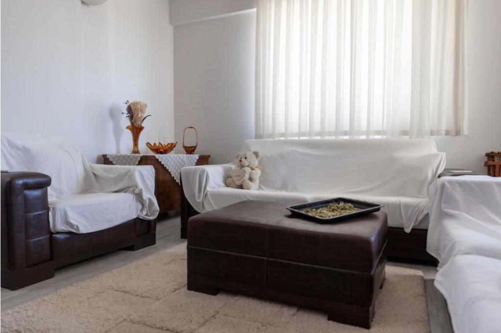 The interior of an empty older family home with dust sheets over the furniture